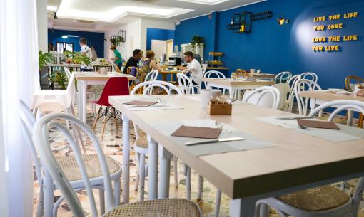 Restaurant moderne avec murs bleus et chaises blanches.