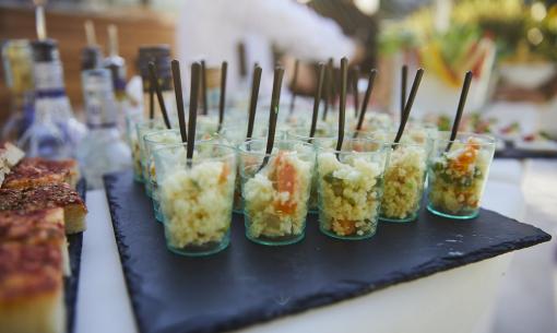 Bicchieri con insalata di cous cous e focaccia su vassoio nero.